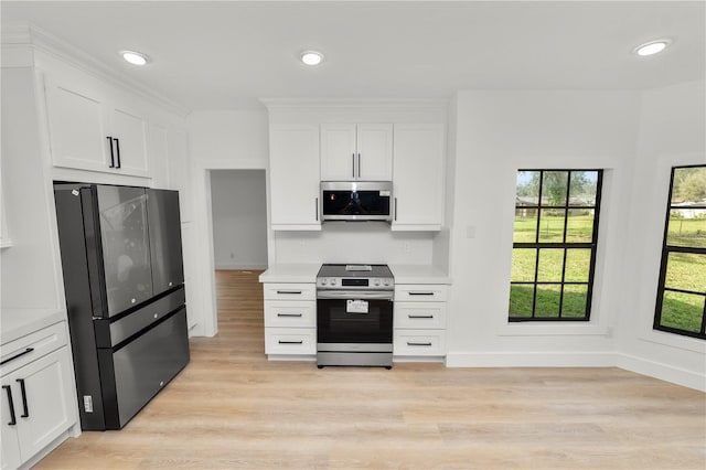 kitchen with recessed lighting, light countertops, light wood-style flooring, appliances with stainless steel finishes, and white cabinets