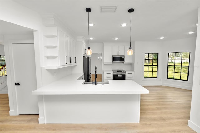 kitchen featuring open shelves, light countertops, hanging light fixtures, appliances with stainless steel finishes, and white cabinets