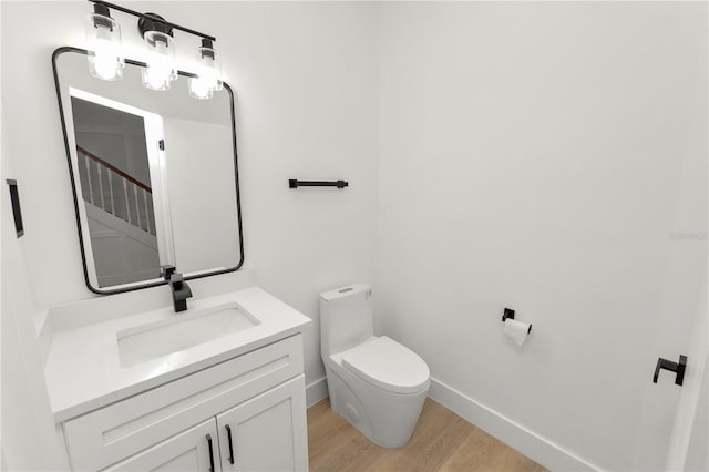 bathroom with toilet, baseboards, wood finished floors, and vanity