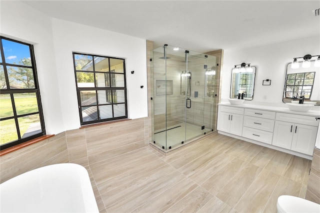 full bathroom featuring a sink, tile walls, a freestanding bath, double vanity, and a stall shower