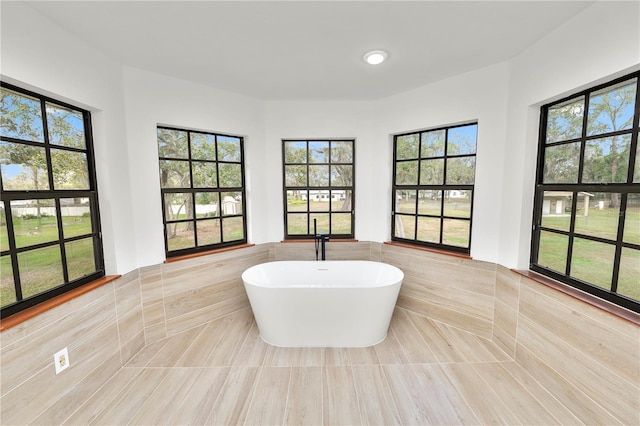 full bath with a freestanding tub, a wainscoted wall, tile walls, and tile patterned floors