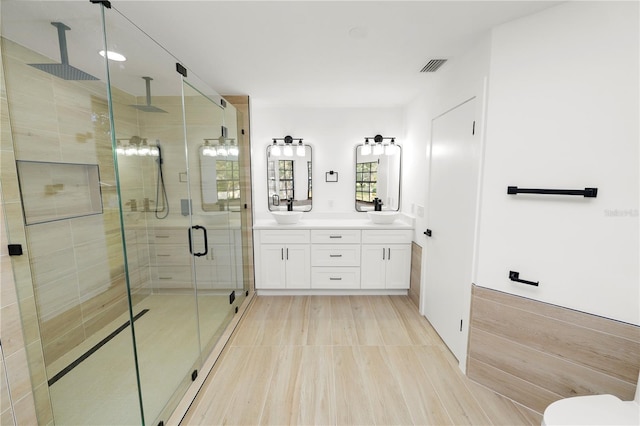 full bath with a sink, double vanity, a shower stall, and visible vents