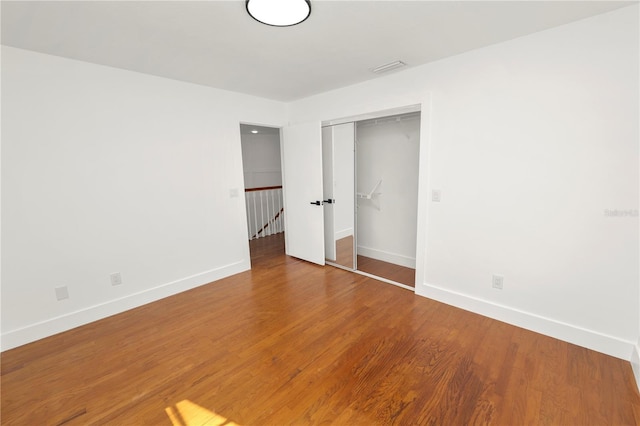 unfurnished bedroom featuring a closet, wood finished floors, and baseboards