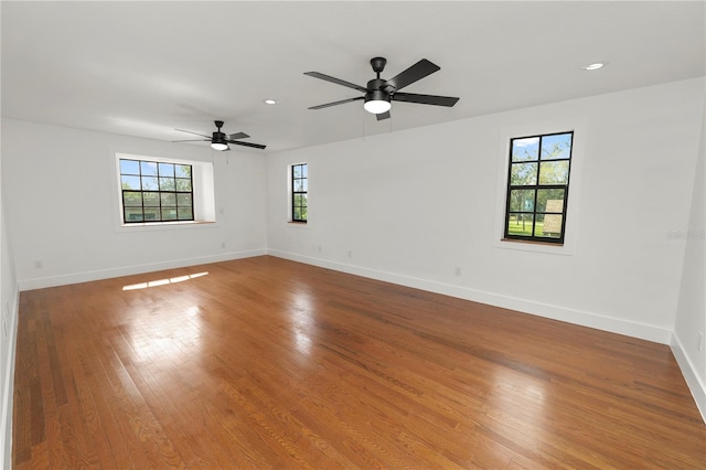 empty room with ceiling fan, recessed lighting, wood finished floors, and baseboards