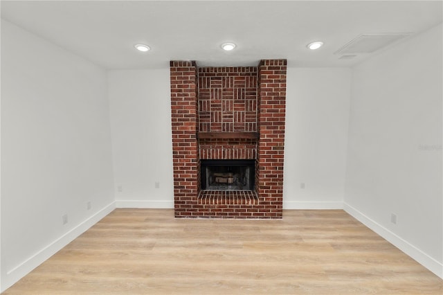 unfurnished living room with a brick fireplace, baseboards, and light wood finished floors