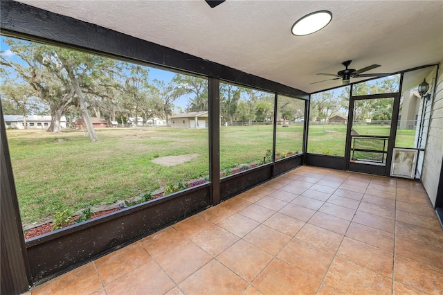 unfurnished sunroom featuring a ceiling fan and a wealth of natural light