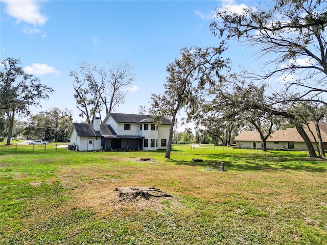 exterior space with a yard, fence, and a chimney