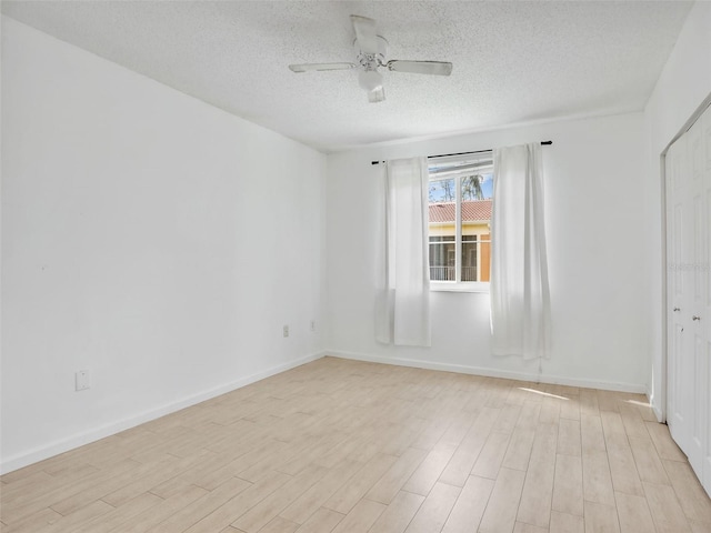 unfurnished room with ceiling fan, a textured ceiling, and light wood-type flooring