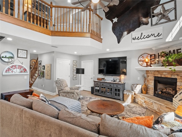 living room featuring a towering ceiling, a fireplace, and ceiling fan