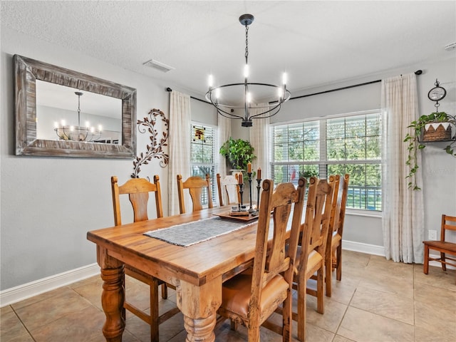 tiled dining space featuring plenty of natural light, a chandelier, and a textured ceiling