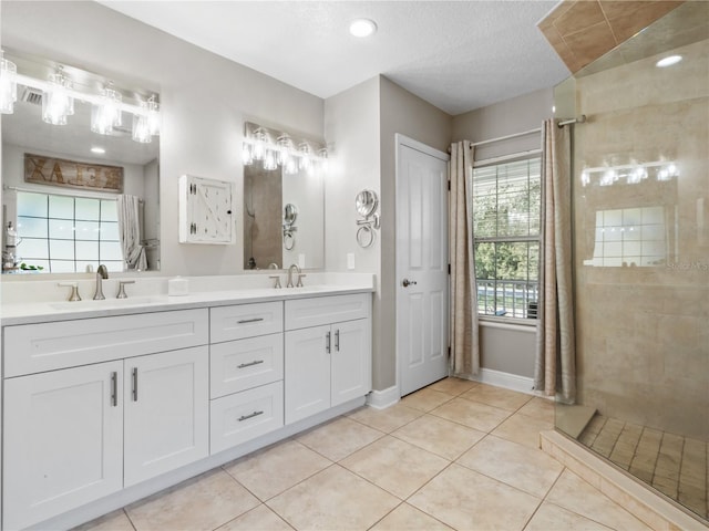 bathroom featuring vanity, tiled shower, tile patterned floors, and a textured ceiling