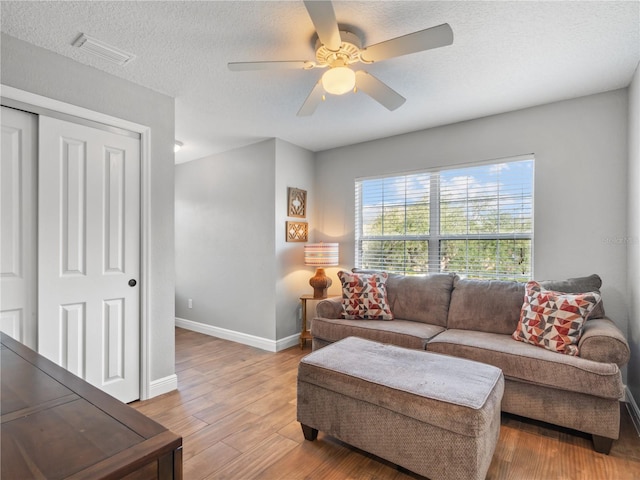 living room with ceiling fan, wood-type flooring, and a textured ceiling