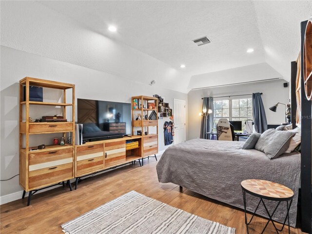 bedroom featuring vaulted ceiling, hardwood / wood-style floors, and a textured ceiling