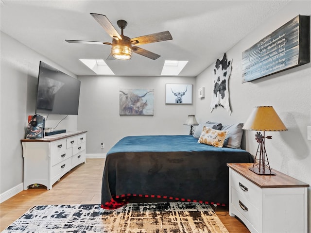 bedroom featuring a skylight, ceiling fan, and light hardwood / wood-style flooring