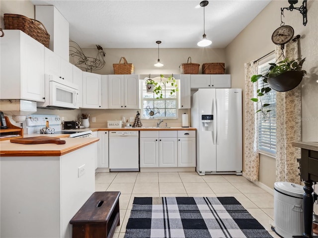 kitchen with light tile patterned flooring, sink, pendant lighting, white appliances, and white cabinets