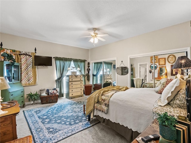 bedroom with carpet floors, two closets, a textured ceiling, and ceiling fan