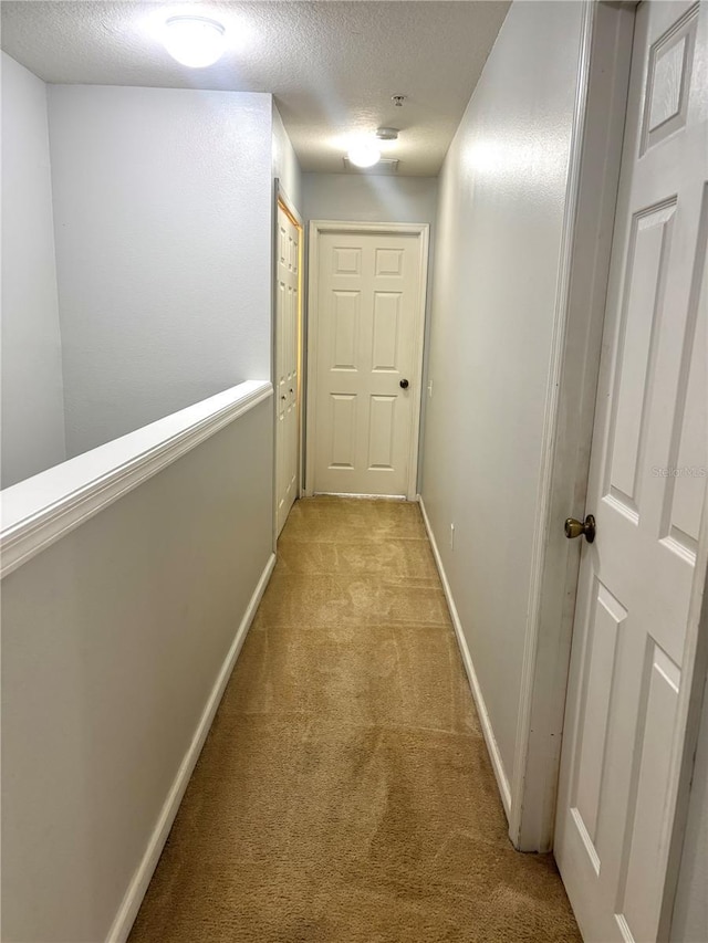 corridor featuring light carpet and a textured ceiling