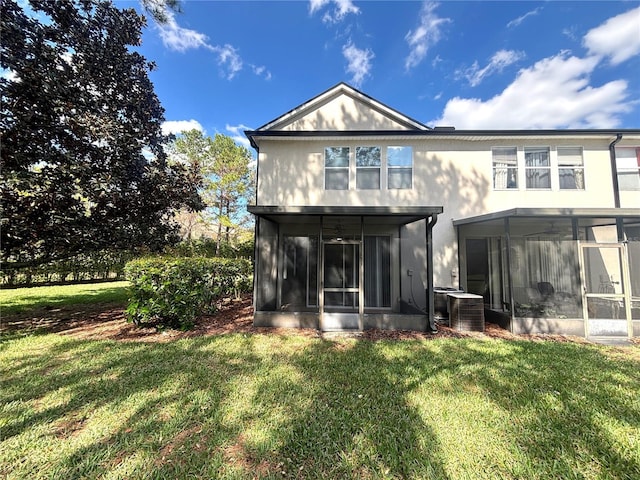 back of property featuring a lawn, a sunroom, and central air condition unit