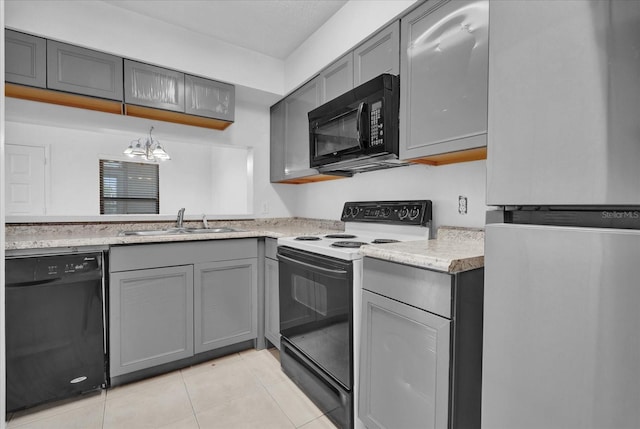 kitchen with light tile patterned floors, gray cabinetry, a sink, black appliances, and an inviting chandelier