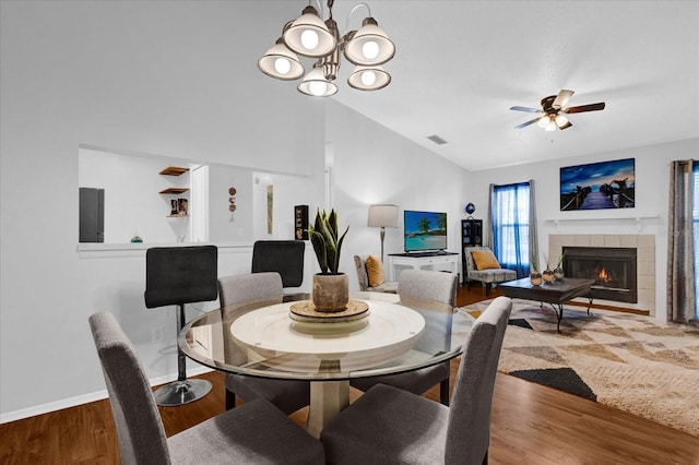 dining space featuring lofted ceiling, a fireplace, visible vents, and wood finished floors