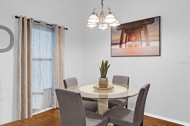 dining space featuring a notable chandelier, baseboards, and wood finished floors