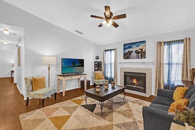 living area featuring visible vents, a tiled fireplace, lofted ceiling, ceiling fan, and wood finished floors