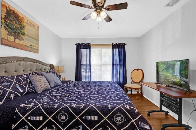 bedroom featuring a textured ceiling, wood finished floors, visible vents, and baseboards