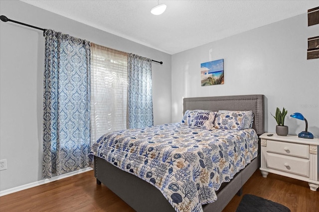 bedroom featuring baseboards, dark wood finished floors, and a textured ceiling