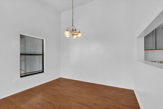 unfurnished room with a chandelier, wood finished floors, and baseboards