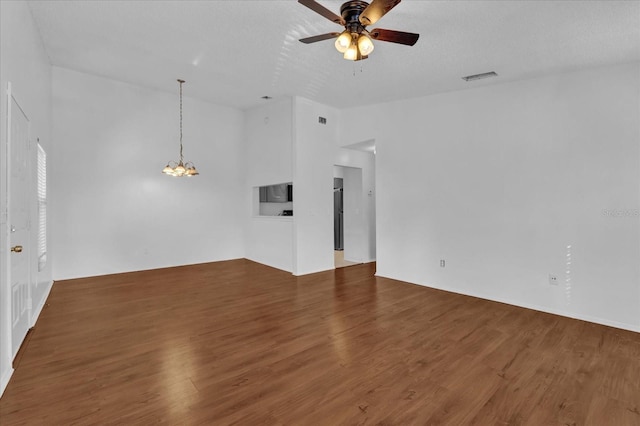 unfurnished room featuring visible vents, vaulted ceiling, wood finished floors, and ceiling fan with notable chandelier