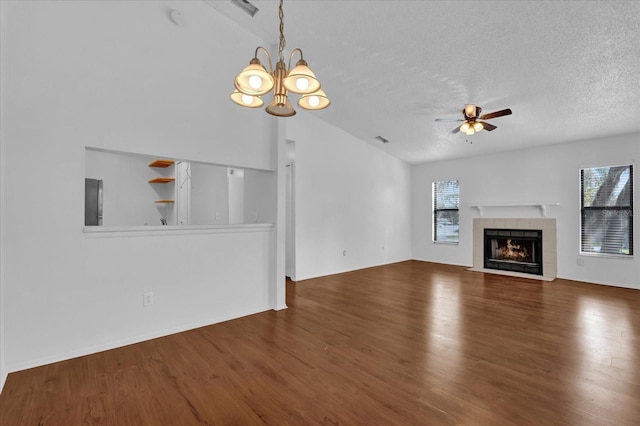 unfurnished living room with ceiling fan with notable chandelier, a wealth of natural light, a fireplace, and wood finished floors