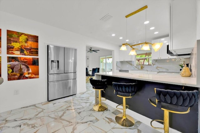 5108 Avignon Ct, Orlando, FL 32839 - kitchen with stainless steel fridge, white cabinetry, light stone counters, a peninsula, and recessed lighting