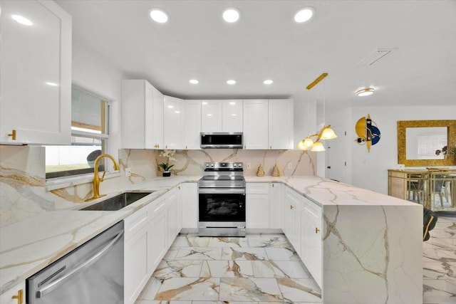 5108 Avignon Ct, Orlando, FL 32839 - kitchen featuring appliances with stainless steel finishes, a sink, light marble finish floors, recessed lighting, and a peninsula