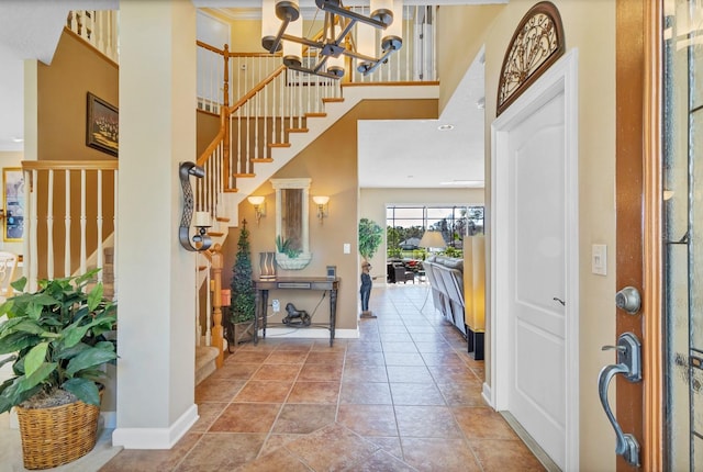 tiled foyer entrance with a towering ceiling and a chandelier