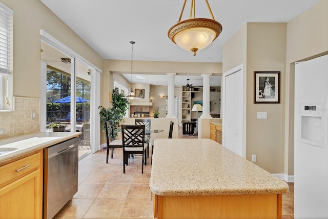 kitchen featuring pendant lighting, a tile fireplace, dishwasher, a kitchen island, and ornate columns