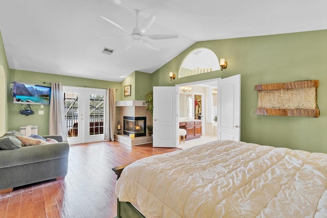 bedroom with lofted ceiling, ceiling fan, access to exterior, a fireplace, and wood-type flooring