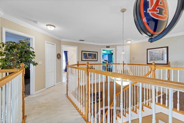 hall featuring a notable chandelier, ornamental molding, and carpet