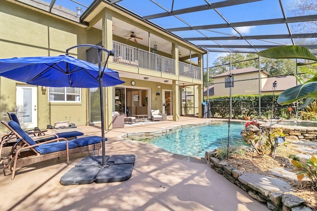 view of swimming pool with glass enclosure, ceiling fan, and a patio area