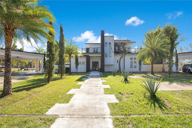 view of front of home with a balcony, stucco siding, and a front yard