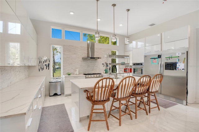 kitchen with tasteful backsplash, white cabinets, wall chimney exhaust hood, modern cabinets, and stainless steel appliances