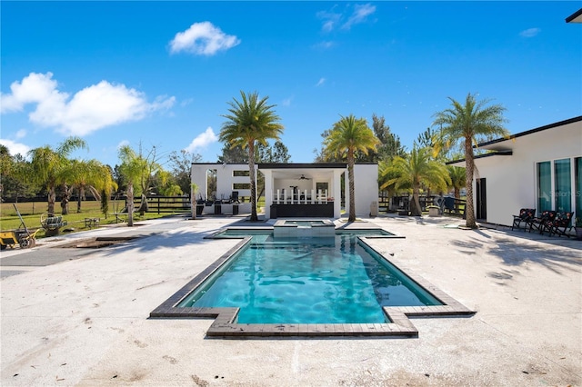 view of pool with a patio, a pool with connected hot tub, fence, and a ceiling fan