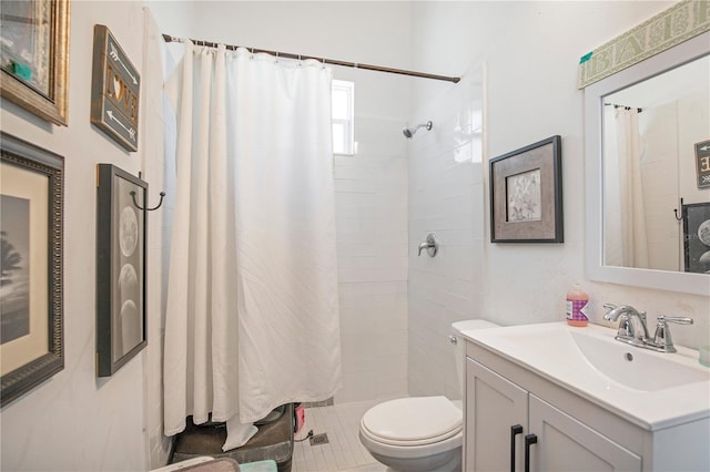 bathroom featuring tiled shower, vanity, and toilet