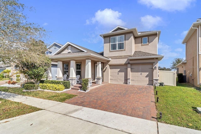 view of front facade with stucco siding, an attached garage, covered porch, decorative driveway, and a front yard