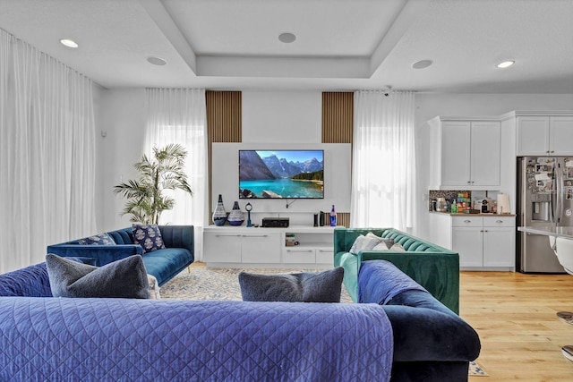 living room featuring light wood-style floors, a tray ceiling, and recessed lighting