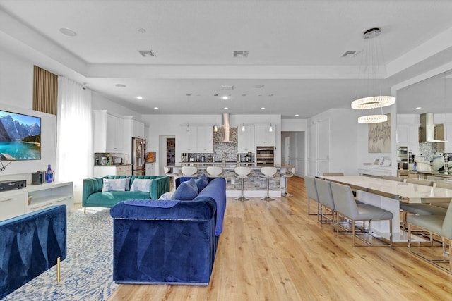 living room featuring light wood-type flooring, visible vents, and recessed lighting