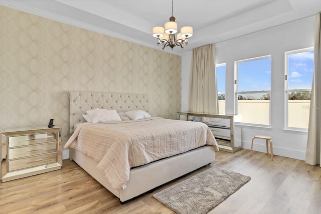 bedroom featuring baseboards, light wood finished floors, a raised ceiling, and wallpapered walls