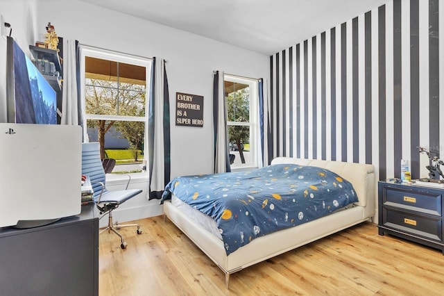 bedroom with an accent wall and wood finished floors