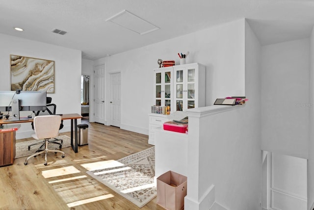 office area featuring baseboards, wood finished floors, visible vents, and attic access