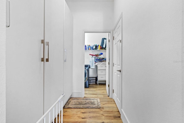 corridor with washer / clothes dryer and wood finished floors