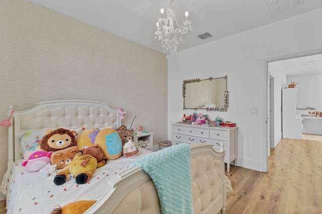 bedroom featuring a chandelier, light wood-style flooring, visible vents, and baseboards